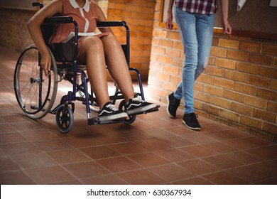 Schoolgirl with her disabled friend in corridor at school