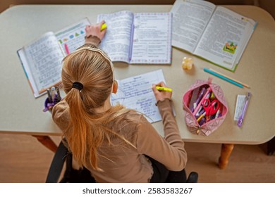Schoolgirl highlighting notes while studying, A girl at a desk highlighting important points in her homework surrounded by books and stationery. Top view