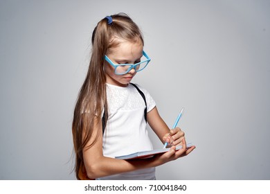 schoolgirl learns to fill a notebook against a gray background, school                                - Shutterstock ID 710041840