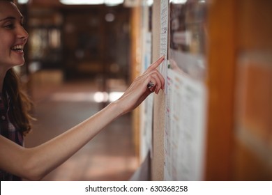 Schoolgirl looking at notice board in corridor at school - Powered by Shutterstock