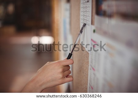 Schoolgirl looking at notice board in corridor at school