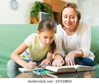 Schoolgirl And Mother Together Doing Homework In Home