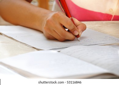 Schoolgirl With Pen Writing Down In Notebook Homework