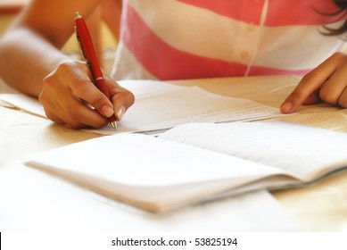 Schoolgirl With Pen Writing Down In Notebook Homework