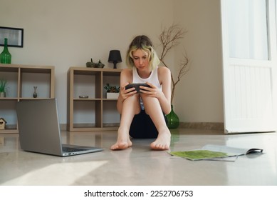 Schoolgirl plays on the phone and ignoring books and studies. - Shutterstock ID 2252706753