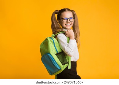 Schoolgirl Posing With School Backpack Smiling To Camera Standing Over Yellow Background. Studio Shot