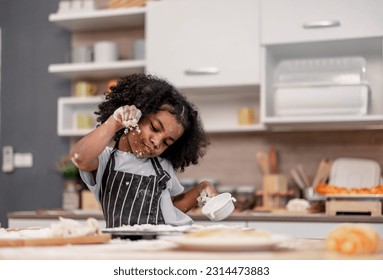 Schoolgirl prepares homemade pizza dough in funny and playful ways. Mixing ingredients like salt, sugar, milk, yeast, oil then rubbing, massaging, pressing bread flour to make it smoother, stretchier
