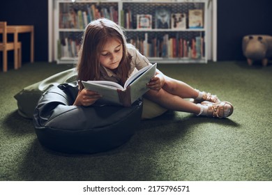 Schoolgirl reading book in school library. Primary school pupil is involved in book. Child doing homework. Smart girl learning from book. Benefits of everyday reading. Child curiosity - Shutterstock ID 2175796571