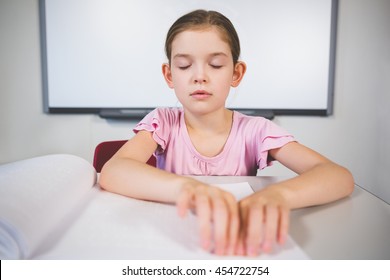 Schoolgirl reading a braille book in classroom at school - Powered by Shutterstock