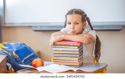 The schoolgirl rested her head on a large stack of school books. The girl was tired during a school lesson. A student rests during a break. Back to school. School supplies and books.
 - Powered by Shutterstock