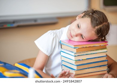 The schoolgirl rested her head on a large stack of school books. The girl was tired during a school lesson. A student rests during a break. Back to school. School supplies and books.
 - Powered by Shutterstock