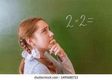 Schoolgirl Solves A Math Problem On The Blackboard During The Lesson.