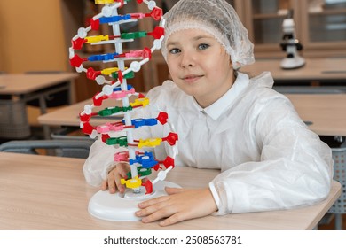 Schoolgirl studying DNA model, in white coat in school classroom. High quality photo - Powered by Shutterstock