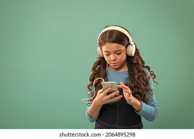 schoolgirl use digital device. casual fashion for kids. kid long hair listen music in headset. small child make play list on smartphone. small girl use mp3 player. study in modern life. copy space