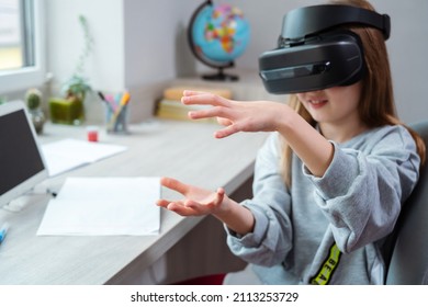 Schoolgirl is using virtual reality simulator headset for study. Child is wearing virtual reality glasses sitting at desk with tablet and touches air with a finger. Future learning concept