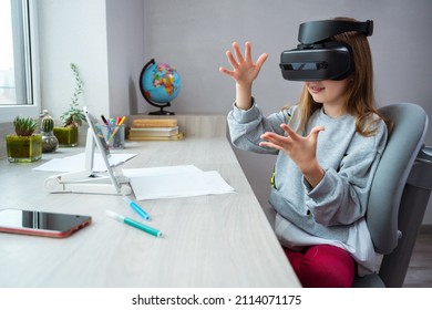 Schoolgirl is using virtual reality simulator headset for study. Child is wearing virtual reality glasses sitting at desk with tablet and touches air with a finger. Future learning concept