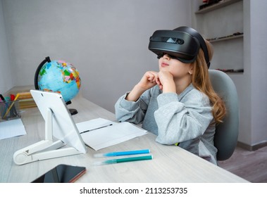 Schoolgirl Using VR Headset Simulators For Studying. Child Is Wearing Virtual Reality Glasses Sitting At Desk With Tablet And Watching On Top. Future Learning Concept