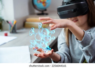 Schoolgirl using VR headset simulators for studying. Child is wearing virtual reality glasses sits at desk watching the structure of the water molecule. Future learning concept - Powered by Shutterstock