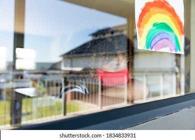 Schoolgirl wearing face mask, looking through a window. Education back to school health safety during Covid19 Coronavirus pandemic. - Powered by Shutterstock