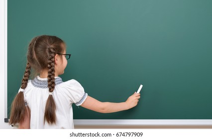 Schoolgirl writing chalk on a blackboard, empty space, education concept - Powered by Shutterstock