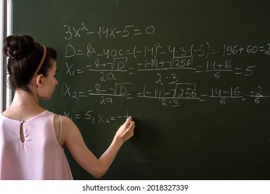 Schoolgirl Writing High School Maths Formula  With Chalk On Blackboard, Math Class Algebra