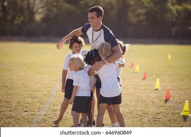 Schoolgirls embracing coach during competition in park - Powered by Shutterstock