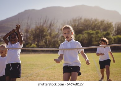 Schoolgirls running toward finishing line during egg and spoon race in park - Powered by Shutterstock