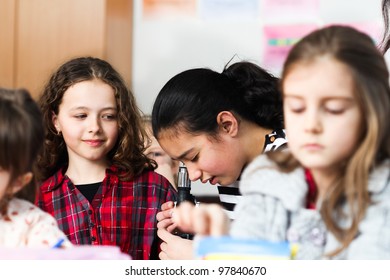 Schoolgirls working with microscope in classroom