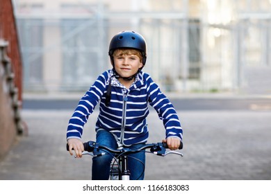 Schoolkid Boy In Safety Helmet Riding With Bike In The City With Backpack. Happy Child In Colorful Clothes Biking On Bicycle On Way To School. Safe Way For Kids Outdoors To School