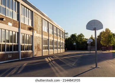 Schoolyard with basketball court and school building exterior in the sunny evening. School yard with playground - Shutterstock ID 2144841935