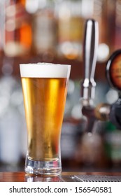 Schooner Glass Of Ice Cold Beer Sitting On Bar Top Near Beer Pouring Tap