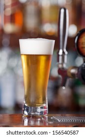 Schooner Glass Of Ice Cold Beer Sitting On Bar Top Near Beer Pouring Tap