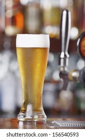 Schooner Glass Of Ice Cold Beer Sitting On Bar Top Near Beer Pouring Tap