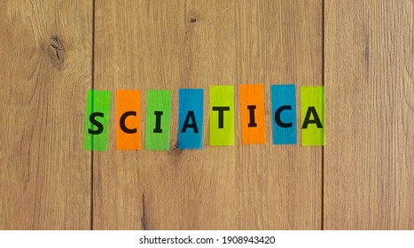 Sciatica symbol. Concept word 'sciatica' on colored papers on a beautiful wooden background, copy space. Medical and sciatica concept. Copy space.
