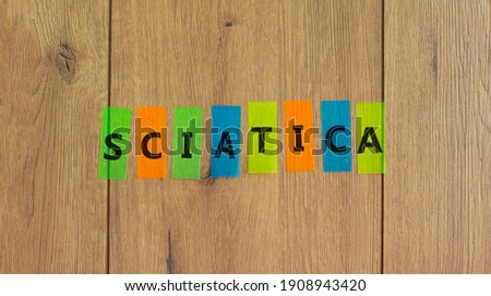 Sciatica symbol. Concept word 'sciatica' on colored papers on a beautiful wooden background, copy space. Medical and sciatica concept. Copy space.