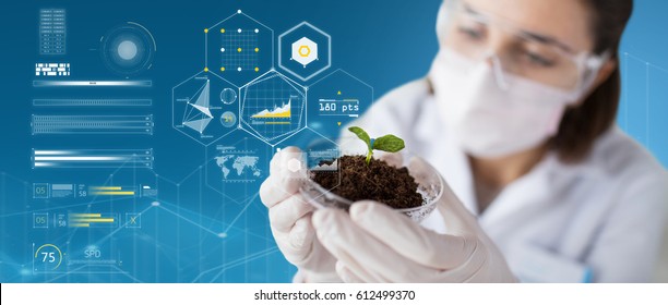 Science, Biology, Ecology And Research Concept - Close Up Of Young Female Scientist Wearing Protective Mask Holding Petri Dish With Plant And Soil Sample Over Blue Background And Virtual Charts