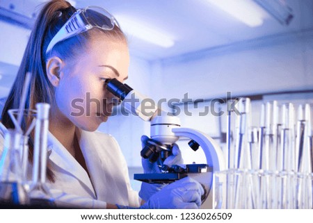 Science Concept. Laboratory Research and Development. Scientific glassware for chemical experiment. Female scientist  working with microscope, laboratory beakers, test tubes, pipettes. Lab interior.