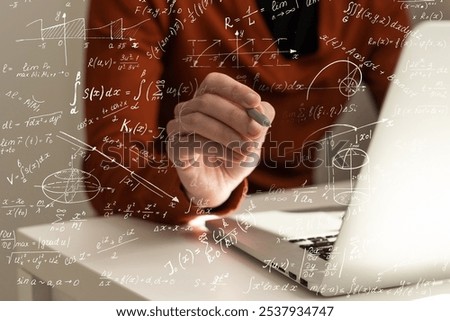 Science and education concept. Illustration of basic physics and mathematics formulas and man working on laptop at table, closeup