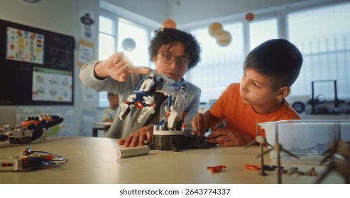 Science and Engineering Lesson: Elementary School Student Studying Model of Innovative Robotic Arm. Teacher Educating Smart Young Boy in Modern Classroom. Interactive Learning and STEM Education. - Powered by Shutterstock - Get 15% off with code: PIKWIZARD15