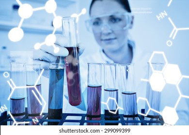 Science graphic against beautiful redhaired woman holding a test tube