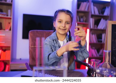 Science, hobbies, learning, education, discovery, childhood and domestic life. Focused Caucasian little girl doing chemistry experiment looking at test tube in evening at living room. - Powered by Shutterstock