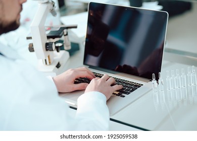 science lab technician using a laptop in the lab.