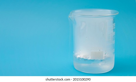 Science Laboratory, Scientific Experiment And Lab Test Concept With Dry Ice In A Glass Chemistry Beaker Isolated On Blue Background With Copy Space