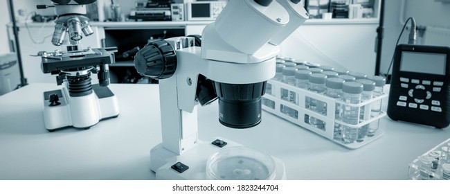 Science Microscope On Lab Bench. Microbiology Laboratory. Blue Toned Image Of Binocular Microscope