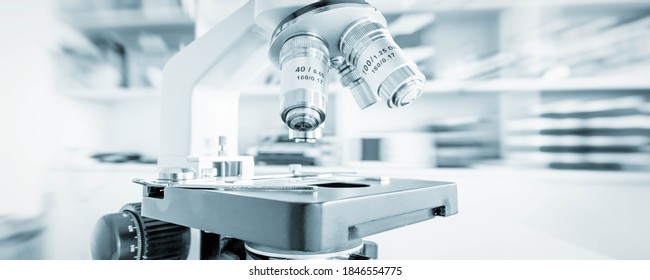 Science microscope on lab bench. Microbiology laboratory. Blue toned image of binocular microscope