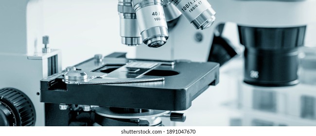 Science Microscope On Lab Bench. Microbiology Laboratory. Blue Toned Image Of Binocular Microscope