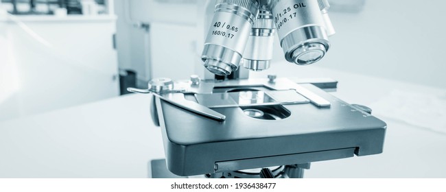 Science Microscope On Lab Bench. Microbiology Laboratory. Blue Toned Image Of Binocular Microscope