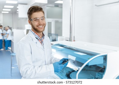 Science Online. Handsome Cheerful Male Scientist Wearing Protective Glasses Smiling To The Camera Using Digital Tablet At The Lab Connectivity 3g 4g Wireless Scientist Internship Concept Copyspace