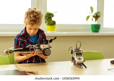 Science Project. Nice Concentrated Boy Holding A Car Model While Thinking About His Project