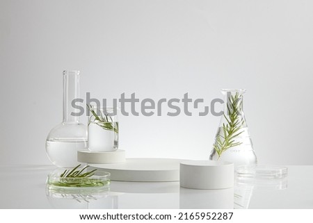Science research on green leaf sample on beaker with fluid and petri dish with white podium in laboratory for develop , white background with glassware for laboratory advertising  